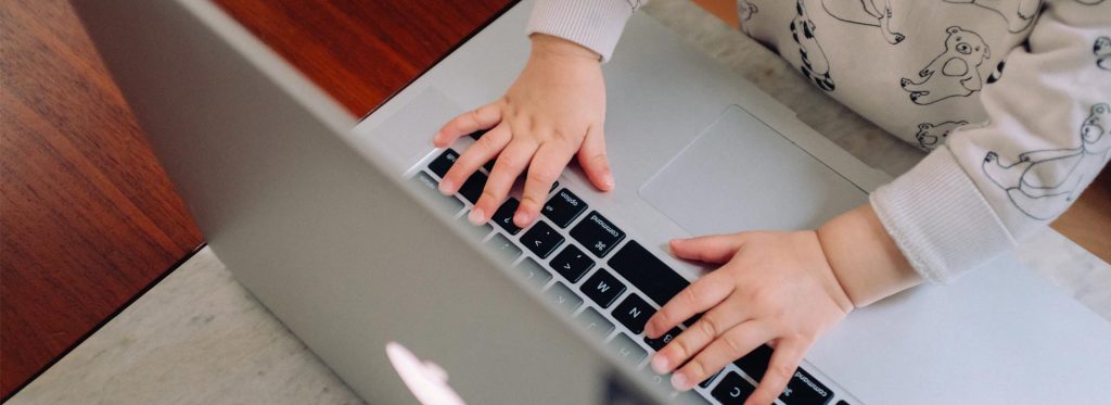 kid typing on apple macbook